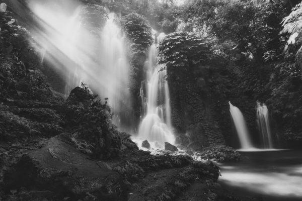 a waterfall in Bali with strong light coming through the mist, black and white